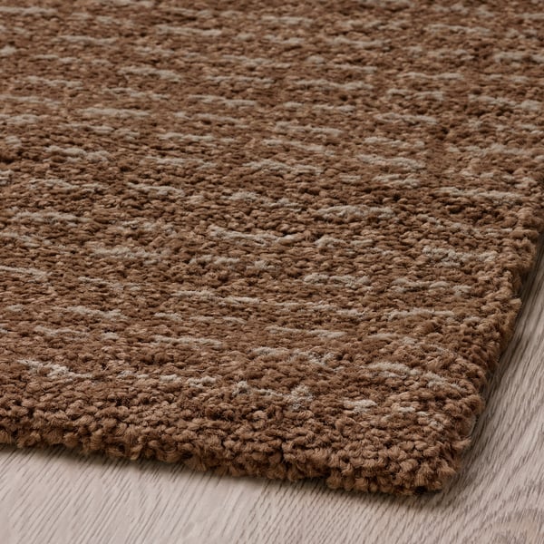 Close-up of a textured, brown rug with a soft, looped weave and patterned details.