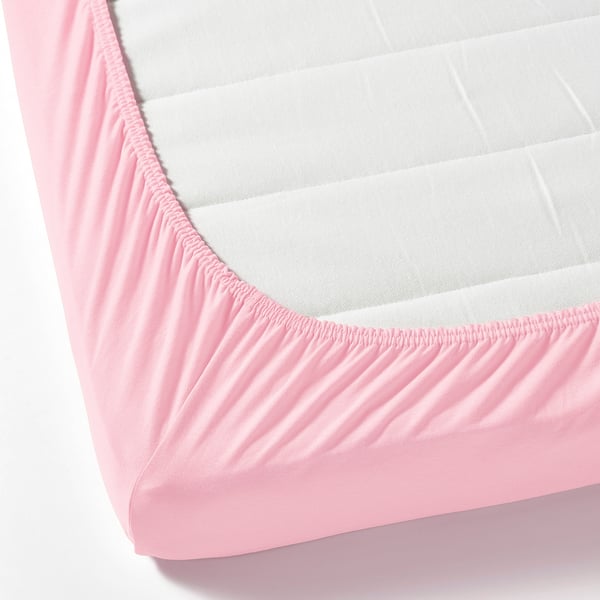 Light pink fitted sheet with elastic edge securing white mattress.