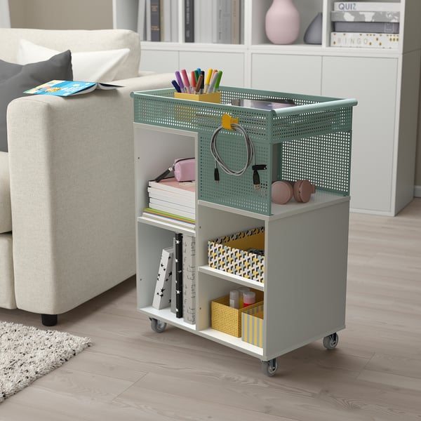 Small grey LYSMASK organiser on wheels, fitting under a large white couch in a tidy room. Holds books, pencils, bags, and boxes.