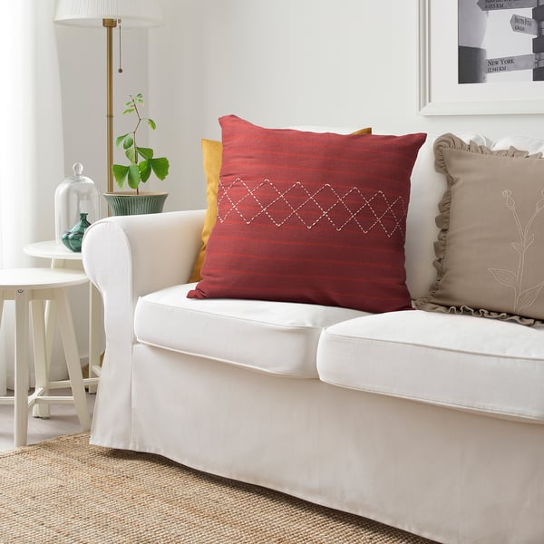 Cosy living room with red MÄVINN stripe cushion, beige & yellow pillows, white lamp, terrarium.