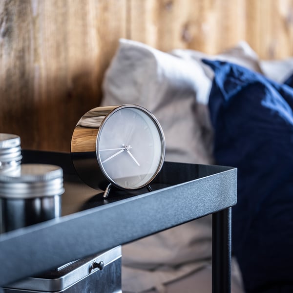 Modern, black MALLHOPPA clock on table, silent with minimalist design.