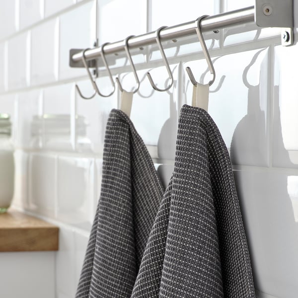 Metal wall rack holding multiple dark grey towels with intricate patterns.