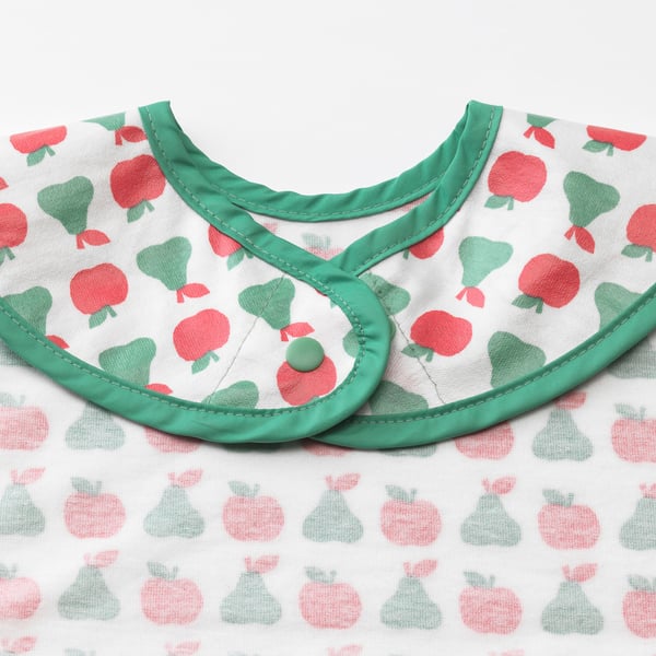Vibrant childrens bib with apple print, green trim, and snap closure. Soft cotton back, waterproof front.