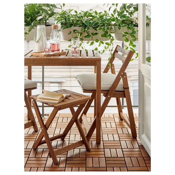 Small balcony setup with wooden furniture, plants, and cushions.