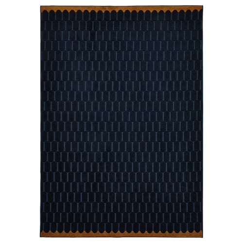 A NÖVLING rug in dark blue with a geometric pattern, made from recycled polyester, rectangular shaped with a scalloped border.