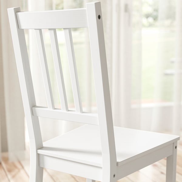 White wood chair with vertical slats on back, sturdy construction near window.