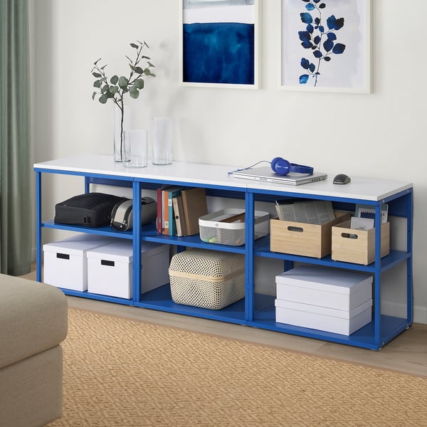 Blue PLATSA shelving unit with multiple storage boxes, laptop, and decor. Fits neatly in room with other items.