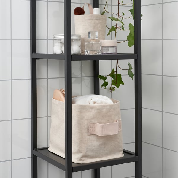 Black metal shelf with woven baskets and toiletries, set against white tiled wall.