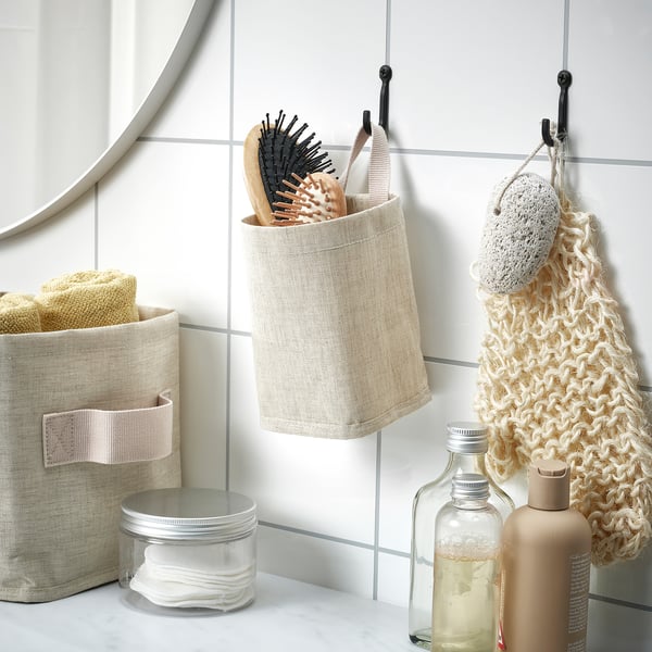 Textile basket holding towels, brushes, and containers on bathroom counter.