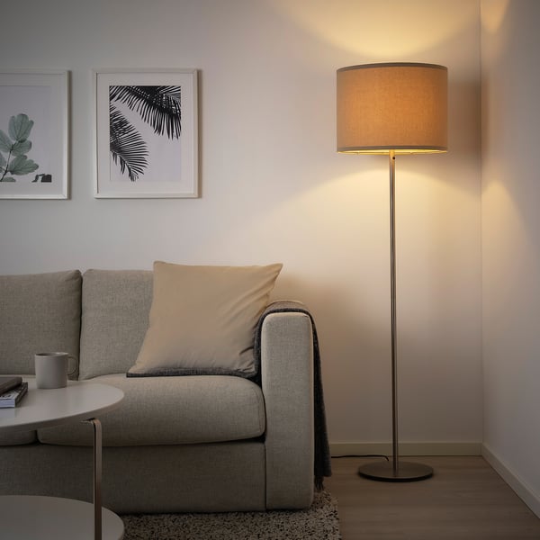 Cosy living room with grey RINGSTA lamp beside sofa, warm light, minimalist decor.