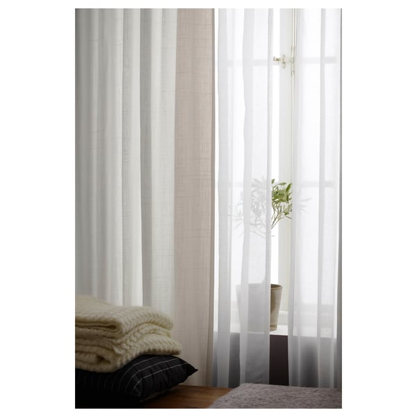 RITVA curtains in white, made from cotton with a linen texture, hanging neatly by a window.