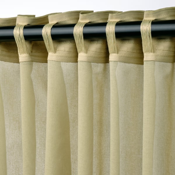 Light olive green sheer curtains hang on black rod, featuring pleated design, allowing filtered light and privacy.