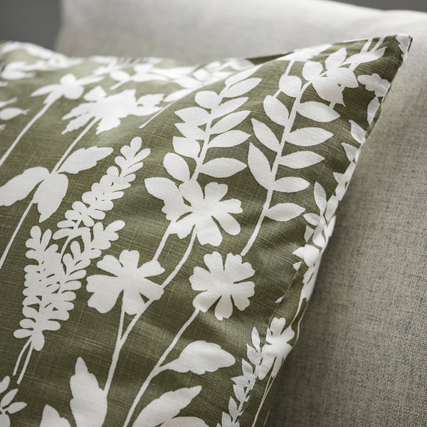 Floral cushion with white patterns on green fabric, showcasing high-quality texture and design.