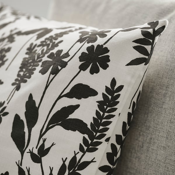 Black floral pillow on white fabric, showcasing elegant craftsmanship.