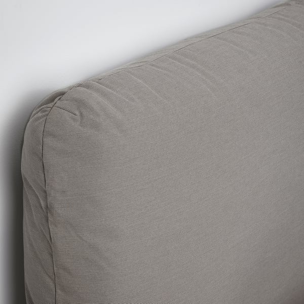 A stylish bed with a gently sloped headboard, upholstered in a soft, textured fabric, resting against a plain wall.
