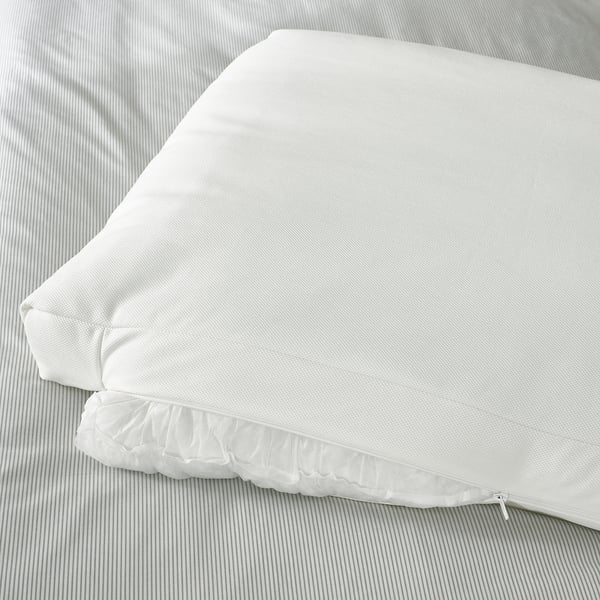White upholstered bed frame with two soft pillows on headboard, placed on striped bedding. Zip visible on edge.