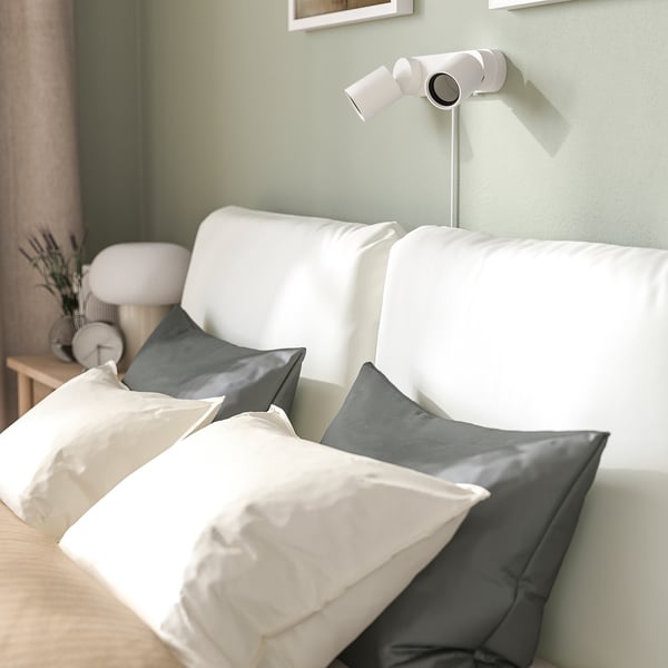 Modern bed with sloped headboard and two pillows, perfect for reading or relaxing.