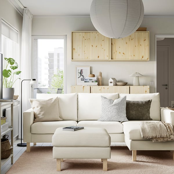 Living room with SALTSJÖBADEN sofa, pillows, wooden unit, lamp, plant, and print.