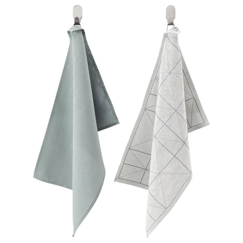 Two SANDVIVA cloths hang, one solid green, one white with grey triangles, made of 50% cotton and 50% lyocell.