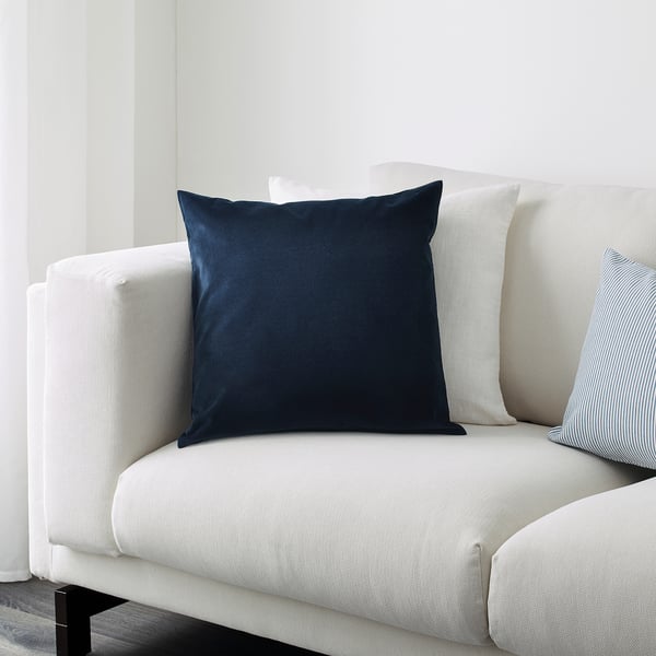 A white sofa with a navy blue throw pillow, showcasing its soft cotton velvet texture.
