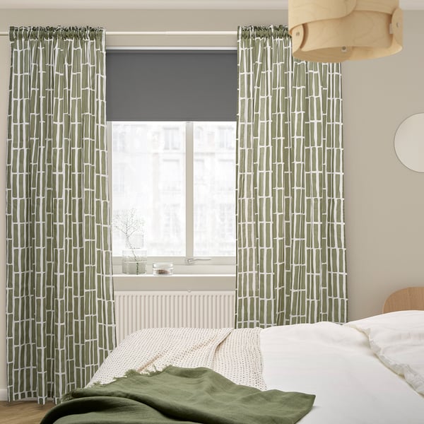 Green SKOGSSTJÄRNA curtains with geometric patterns in bedroom, covering large window.