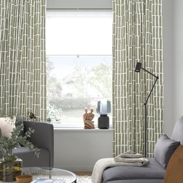 Modern living room with green SKOGSSTJÄRNA curtains. Couch, chair, and lamp by large window.