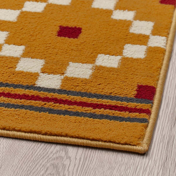 Vibrant yellow rug with red and white patterns. Soft texture, high quality, and warm colours.