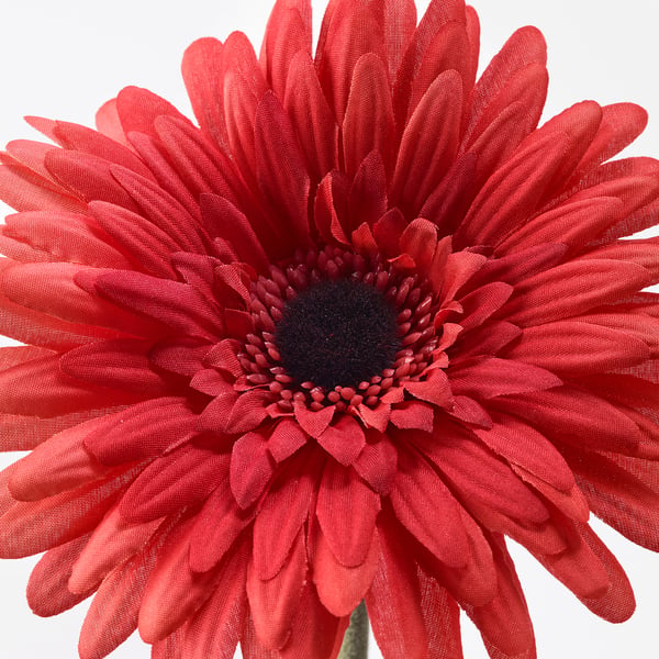 Bright red artificial flower, highly detailed with realistic petals and centre, set against white background.