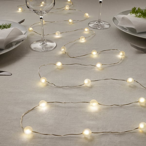 String lights decorate a table set for a festive meal, featuring warm white led bulbs powered by batteries.