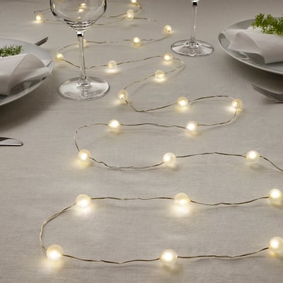 String lights decorate a table set for a festive meal, featuring warm white led bulbs powered by batteries.