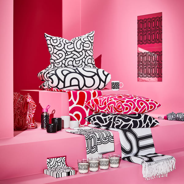 Black and white patterned pillows, cups, and blankets on pink shelves, with a sötrnon decorative mirror.