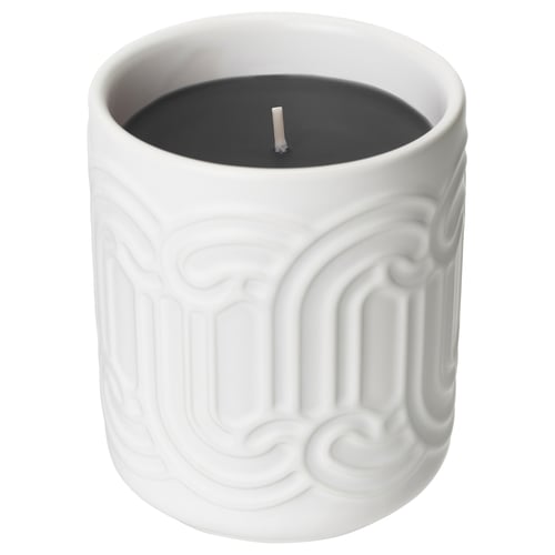 A white ceramic SÖTRÖNN candle with black wax a textured, curved design. It emits a vanilla-berry scent.