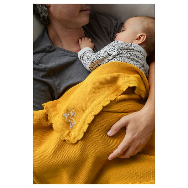 Adult holding baby under yellow SOLGUL cotton blanket.