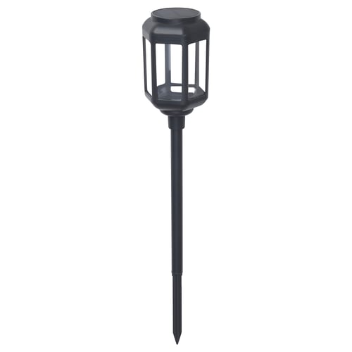 A black, cylindrical SOLVINDEN solar-powered outdoor lamp with a spike base. The shade is transparent polycarbonate, and it a modern design.
