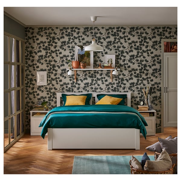 Modern bedroom with floral wallpaper, blue bedding, wooden floors, and a chic pendant light.