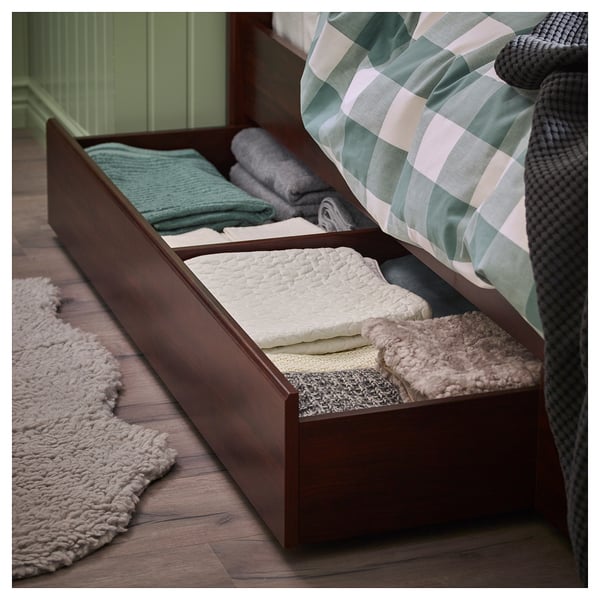 Under-bed storage drawers shown with folded blankets and linens, made of dark brown wood.
