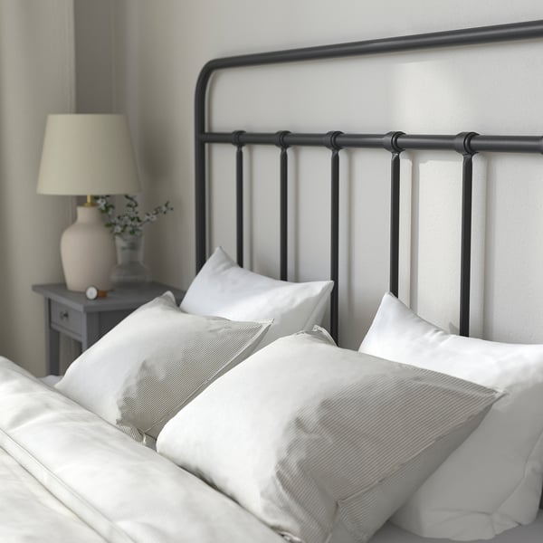 Cosy bed with metal frame, white linens, and bedside table. Lamp included.