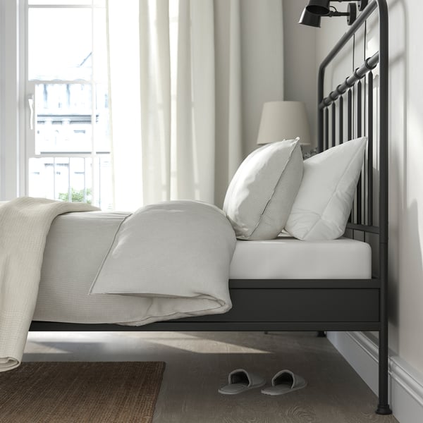 Bedroom with STJÄRNÖ bed, curved head & footboard, white bedding, lamp, slippers.