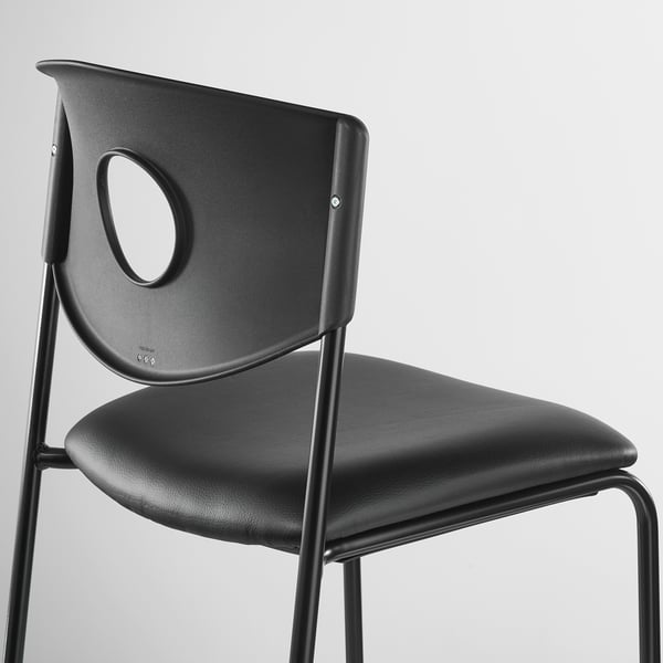 Black modern chair with circular cutout in backrest, sturdy metal legs, sleek design.