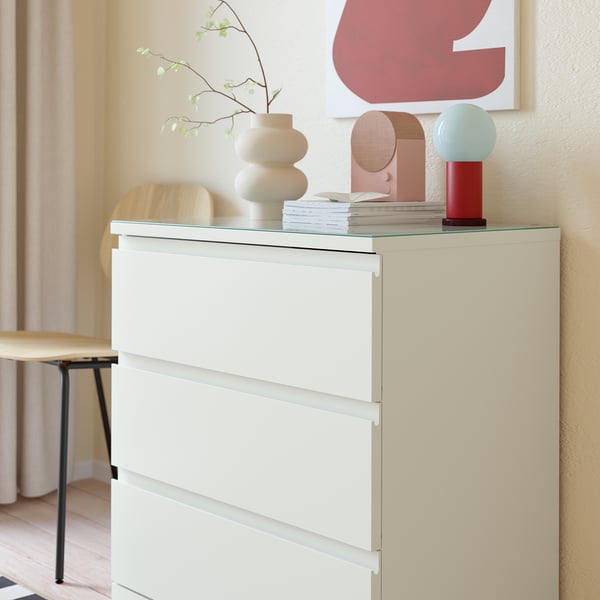 Modern chest with glass top for protection, displaying decor and photos.