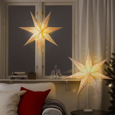 Decorated room with lit star lamps, a red pillow, and a small christmas tree, creating a festive atmosphere.