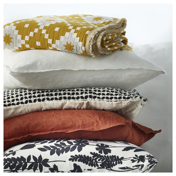 Stack of 5 pillows: yellow & white chequered, white, brown textured, orange, black floral.