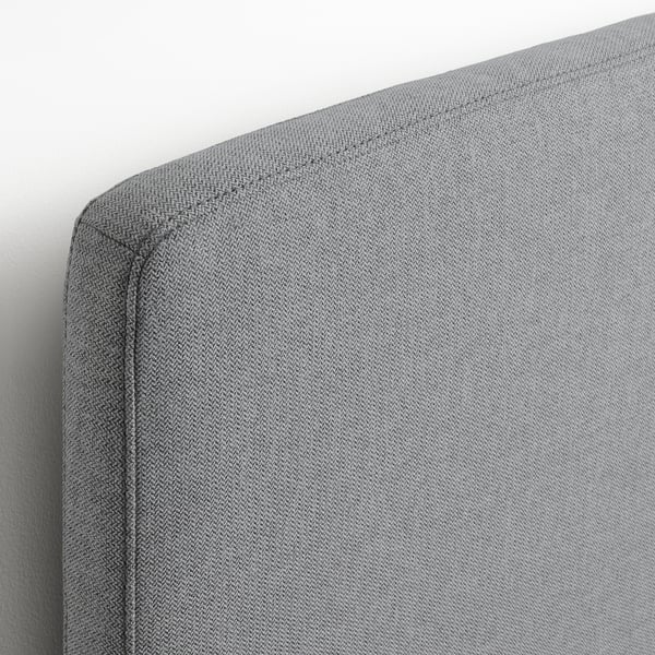 Close-up of a grey upholstered headboard with neat stitching, showcasing quality fabric and design.