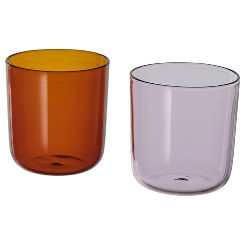 Two colourful glass cups: one brown with yellow interior, one light purple. Round shape, simple design. Ideal for drinks.