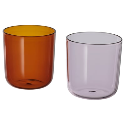 Two colourful glass cups: one brown with yellow interior, one light purple. Round shape, simple design. Ideal for drinks.