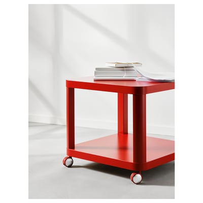 Bright red TINGBY side table with castors. Square, minimalist design. Holds stack of books. Fits small spaces. Moveable.