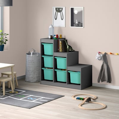 Kids playroom with blue TROFAST storage, dark frame, toys, jacket.