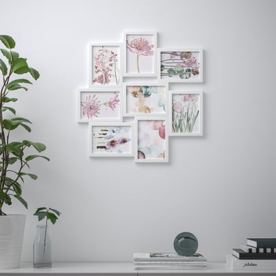 Wall display with six white-framed floral art cards arranged neatly. Below, a shelf holds plants, books, and decorative sphere.