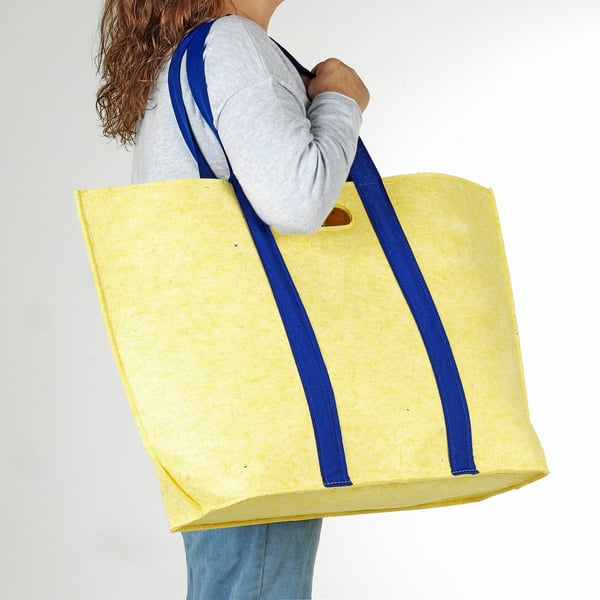 Person carrying large yellow bag with blue straps.