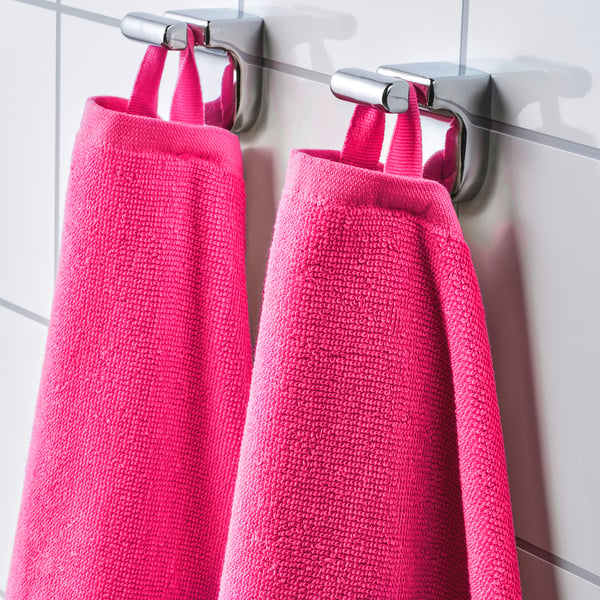 Two bright pink towels hang side by side on silver hooks. The towels are soft, absorbent, and fast-drying terry cloth.